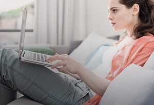 eine Frau, die auf einem Sofa sitzt und einen Laptop benutzt