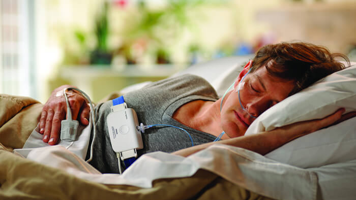 Foto von einem seitlich schlafenden Mann im Bett, der einen Philips Schlaftest macht