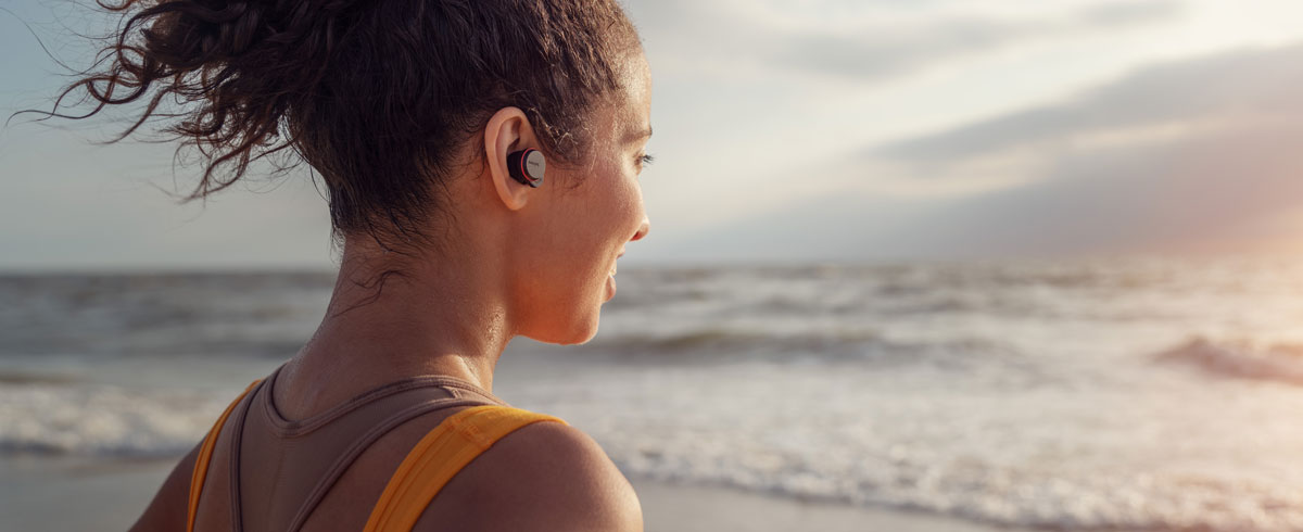 Femme portant un casque sport Philips véritablement sans fil à la plage