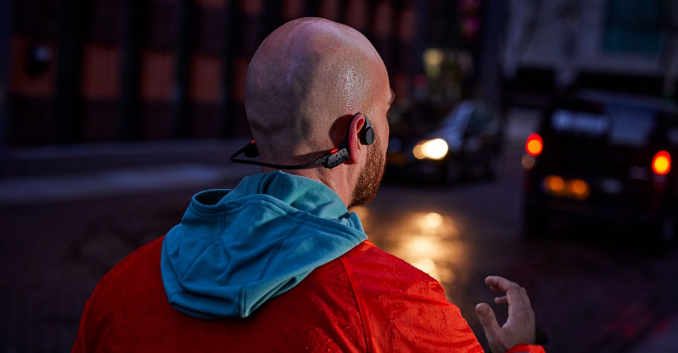 Mann trägt offene Kopfhörer auf einer überfüllten Straße