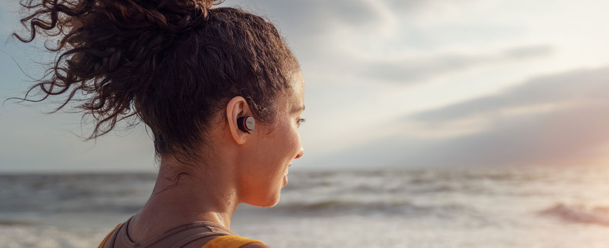 Frau, die True Wireless Kopfhörer am Meer verwendet