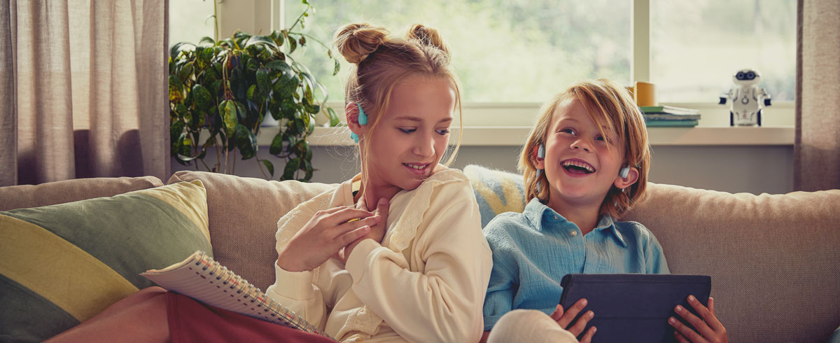 Kinder, die Philips Open-Ear-Kopfhörer für Kinder verwenden, um ein Video anzusehen und sich freuen