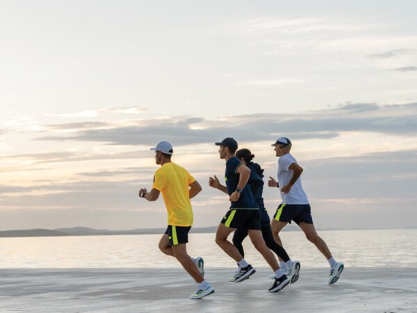 Vier Teilnehmer des Laufs laufen zusammen am Strand.